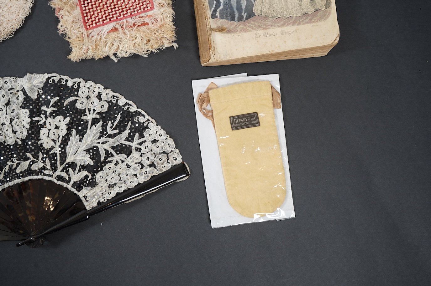 A French tortoiseshell, net, sequin and Honiton bobbin lace fan, with a collection of Jet appliques, a bead work fronter, embroidered mats and silk mats, an early Tiffany &Co poshette and embroidered appliqués and a Le M